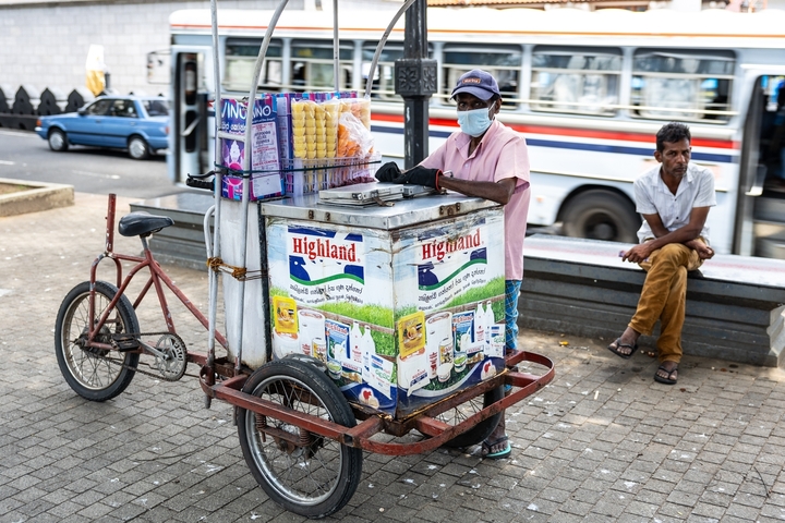 A man selling goods from a bicycle cart on the street.