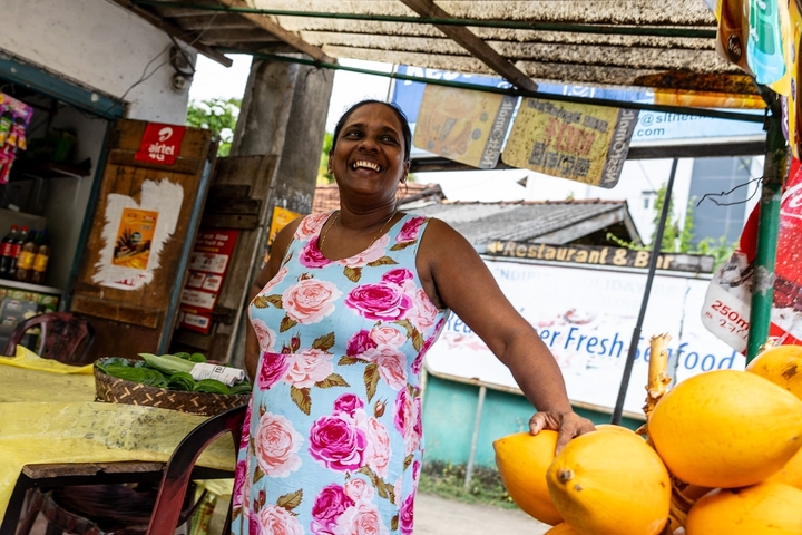       A woman smiling while standing at a street stall.
  