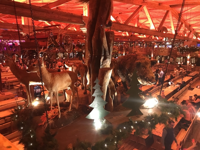 Indoor setting with animal figures and people seated at tables.