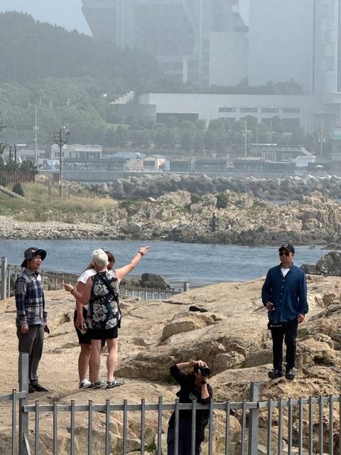       A group of people on rocky terrain by water.
  