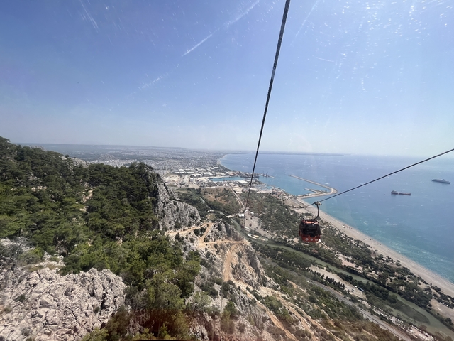       Aerial view of the coast with mountains and a cable car.
  