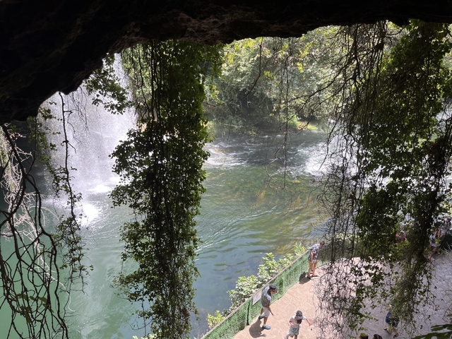       Scenic view of waterfall and river through greenery.
  