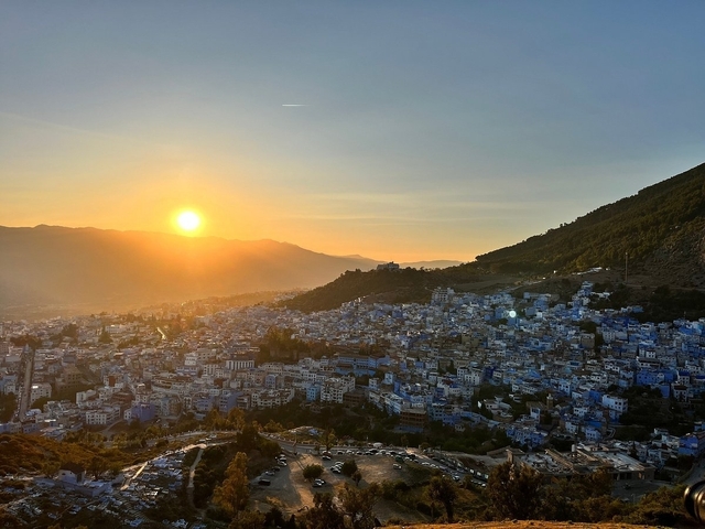       Cityscape at sunset with mountains in the background.
  