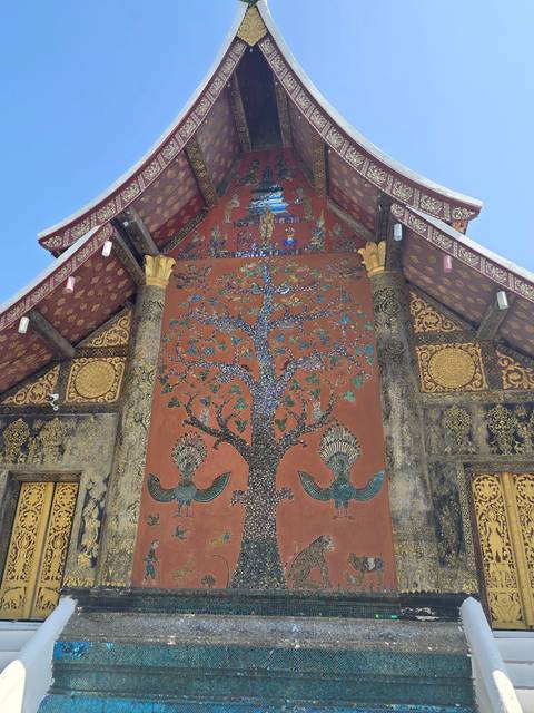 Colorful mural with intricate design and tree imagery on a temple wall.