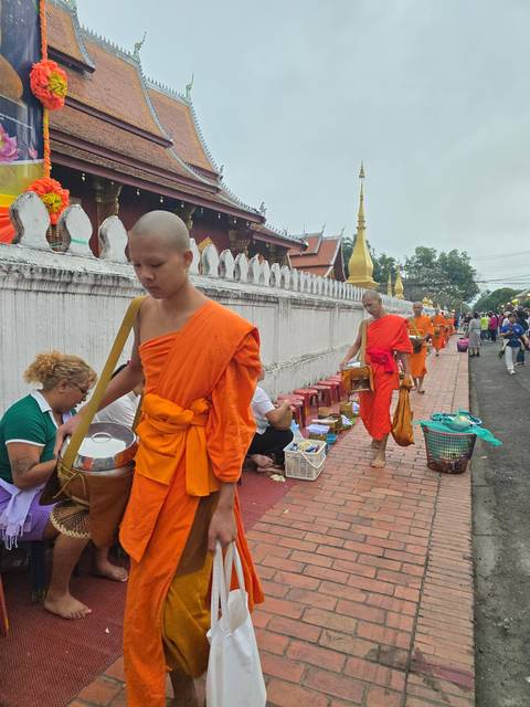 Monks in traditional orange robes during a ceremony with onlookers.