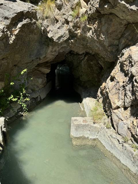 Cave entrance with water and rocky surroundings.