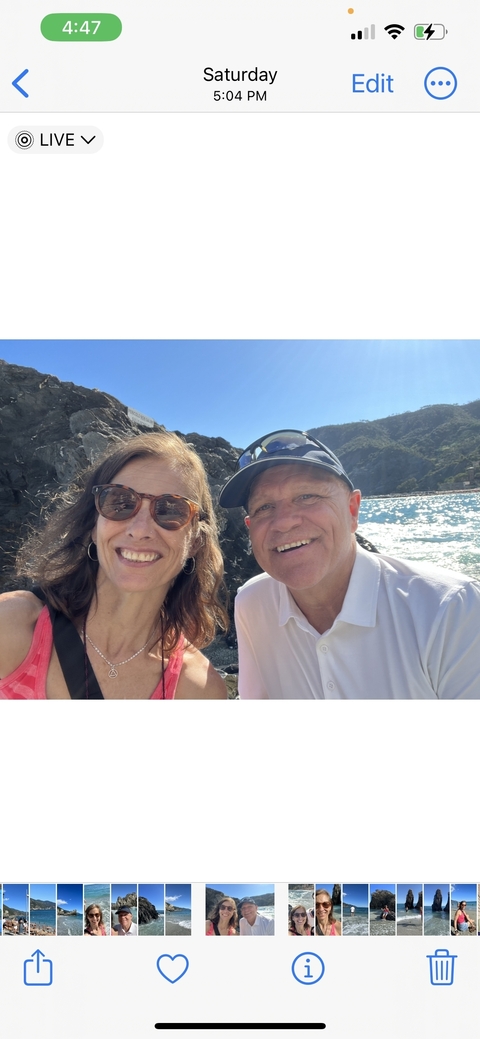       Couple taking a selfie with the sea and mountains in the background.
  