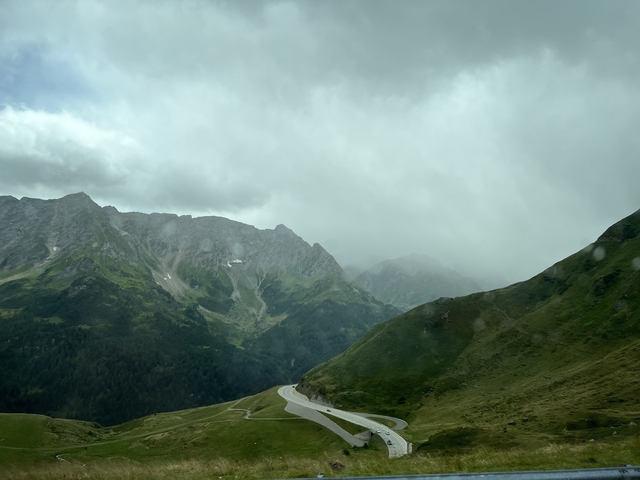       Cloudy mountain landscape with a winding road.
  