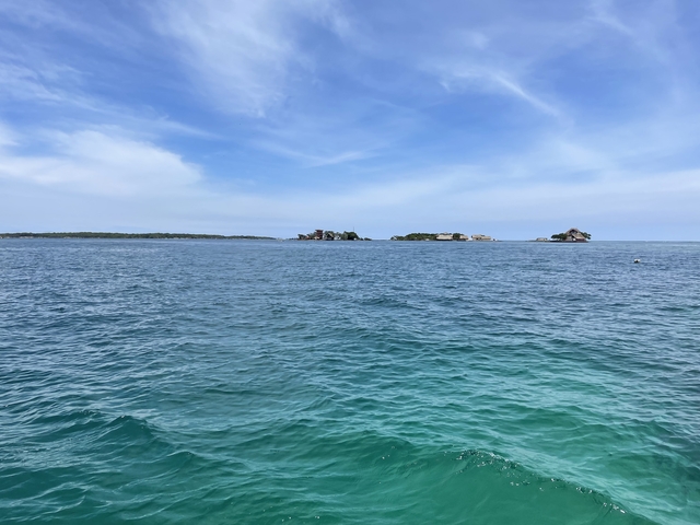      Open sea with distant islets under a blue sky
  