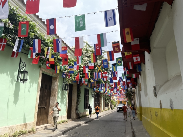       Street with colorful flags and people walking
  
