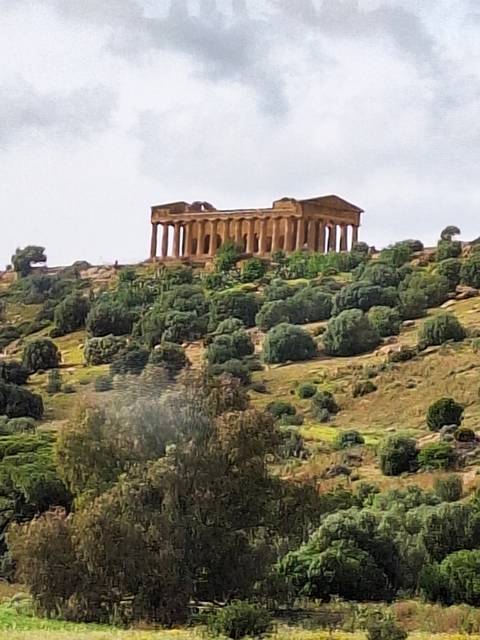 An ancient temple on a hill with greenery.