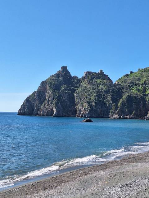 A rocky cliff with blue sky and ocean view.