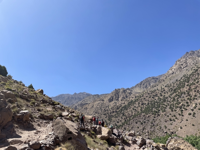       Group of hikers on a trail in mountainous terrain.
  