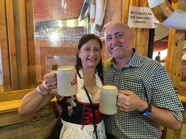 Couple holding large beer mugs at a beer festival.