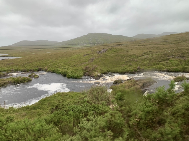 River in a green landscape with hills in the background.