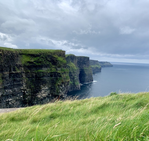 Dramatic ocean cliffs under a cloudy sky.