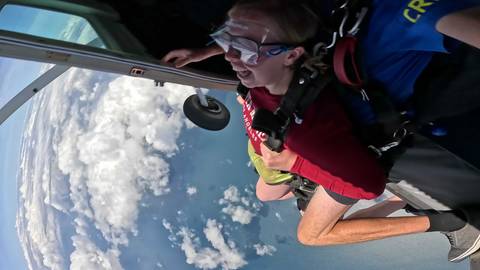       Tandem skydivers looking out from an airplane.
  