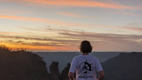       Person watching a sunset over a mountainous landscape.
  