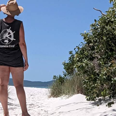       Person standing beside dunes with foliage.
  