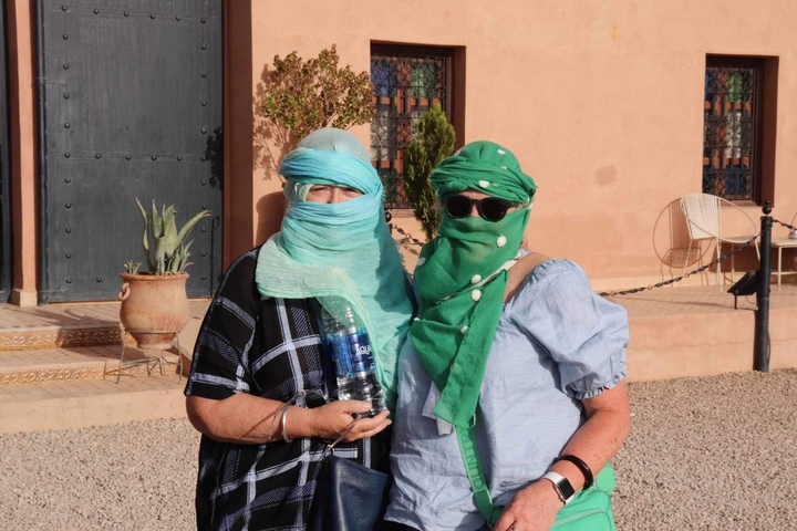       Two women in scarves posing in front of a building.
  