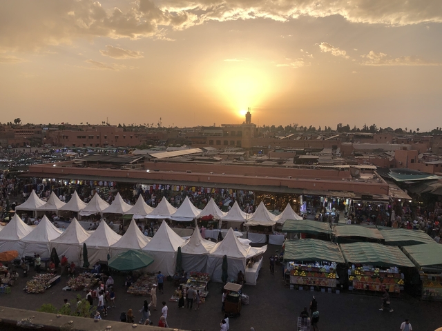       A bustling market with tents and people at sunset.
  