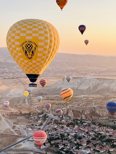      Hot air balloons floating over a rugged landscape.
  