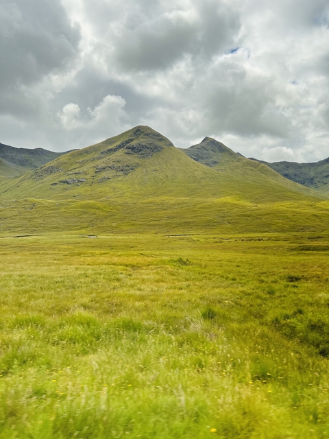 Rolling green hills with patches of sunlight.