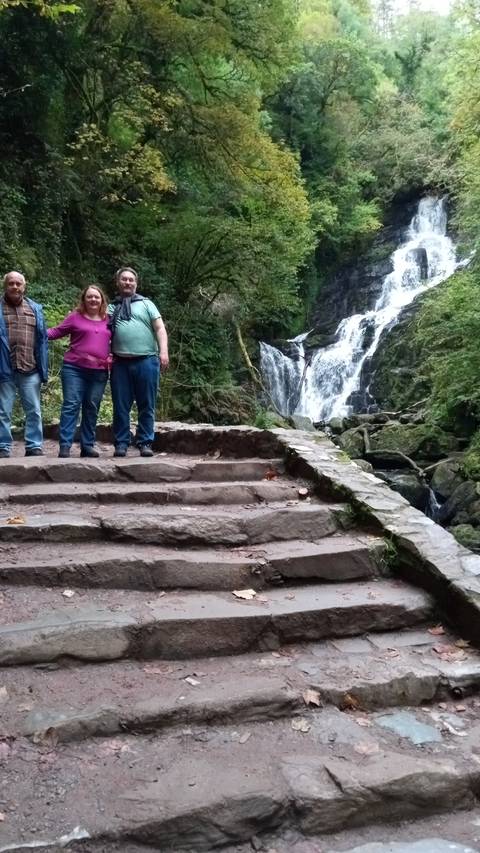 Waterfall with people posing on stone steps.