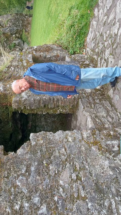 A person standing by an old stone structure.