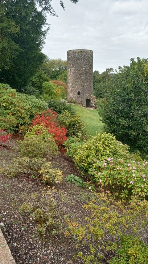       A garden with a historic round tower.
  