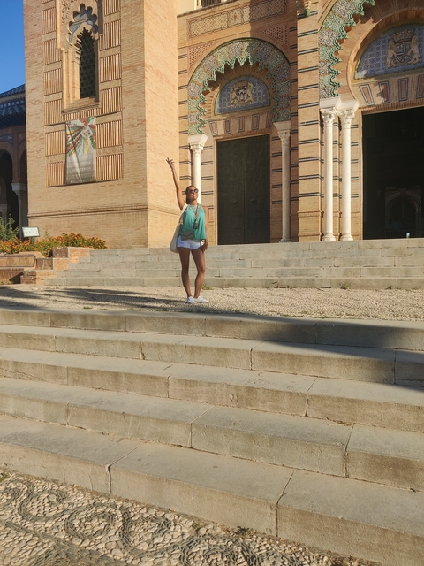 Woman posing on stone steps in front of an impressive building.