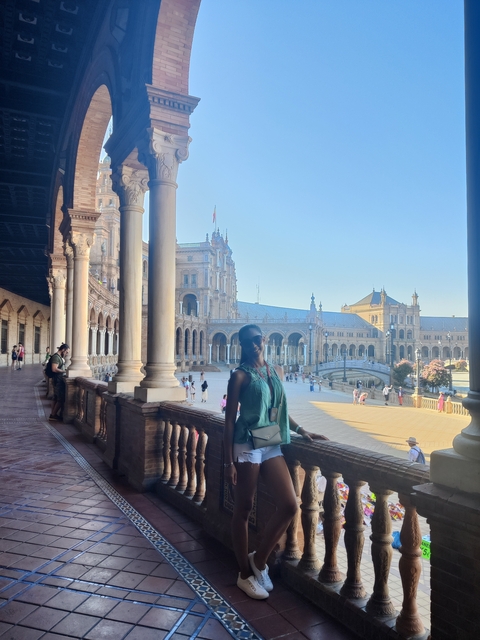       Woman posing at Plaza de España with buildings in the background.
  