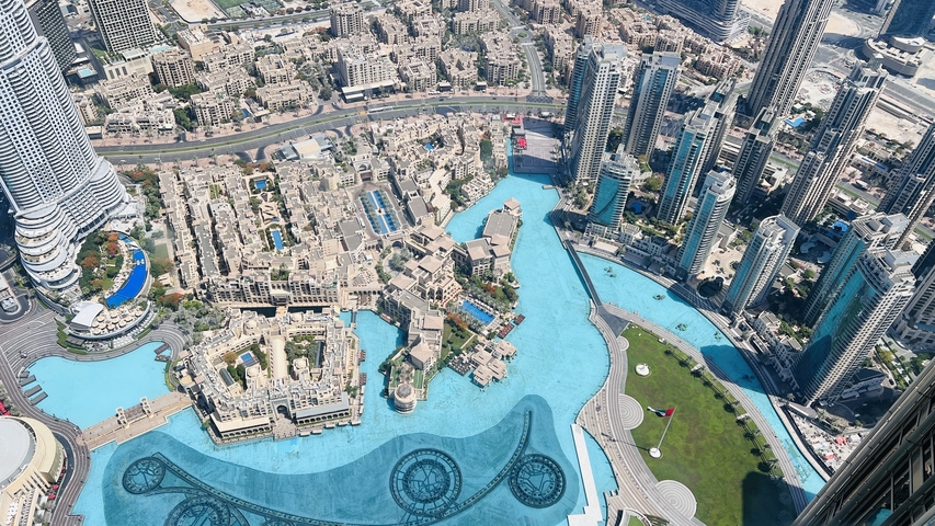       Aerial view of a cityscape with modern skyscrapers and a large water feature.
  