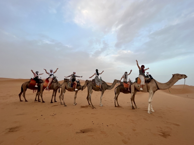 Line of camels with riders in a desert.