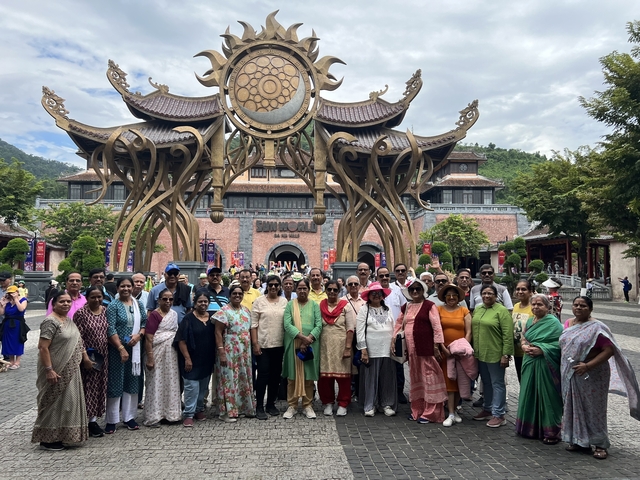 Group photo in front of an ornate entrance with a mountainous background.