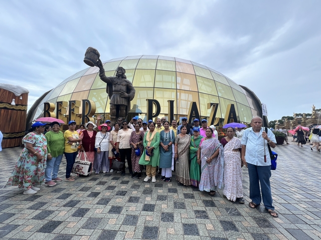 Large group of people posing in front of a dome-shaped building with a statue.