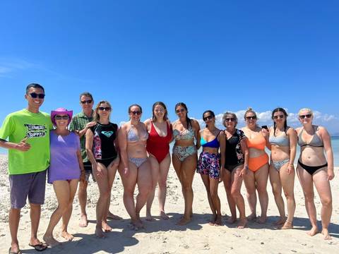      Group of people at a beach with blue sky.
  