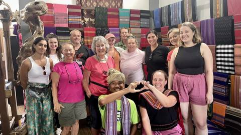       Group of people in a shop with colorful textiles.
  