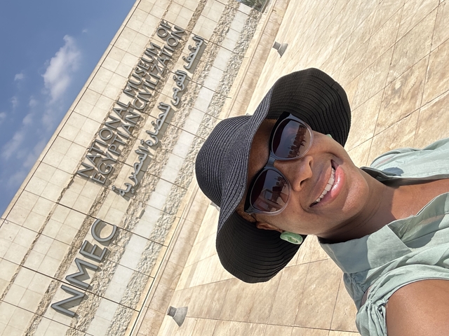 Person smiling in front of the National Museum signage.