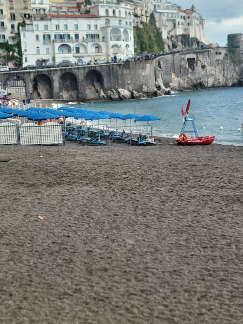 Beach with umbrellas and people relaxing on loungers.