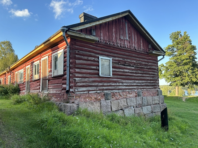       Side view of a red wooden house with stone base.
  