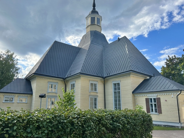       Church with a dark, intricate roof against cloudy sky.
  