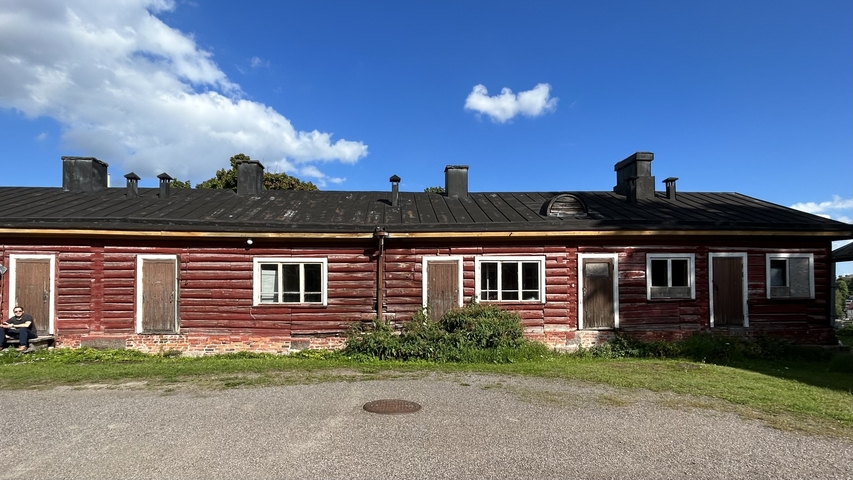       Red wooden building with a man visible on the left.
  