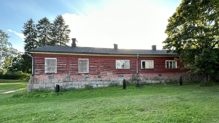       Red wooden building surrounded by greenery.
  