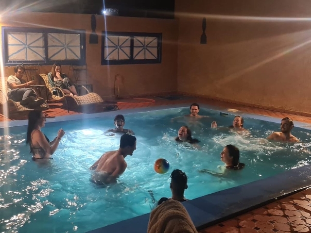 A group of people enjoying a swimming pool indoors.
