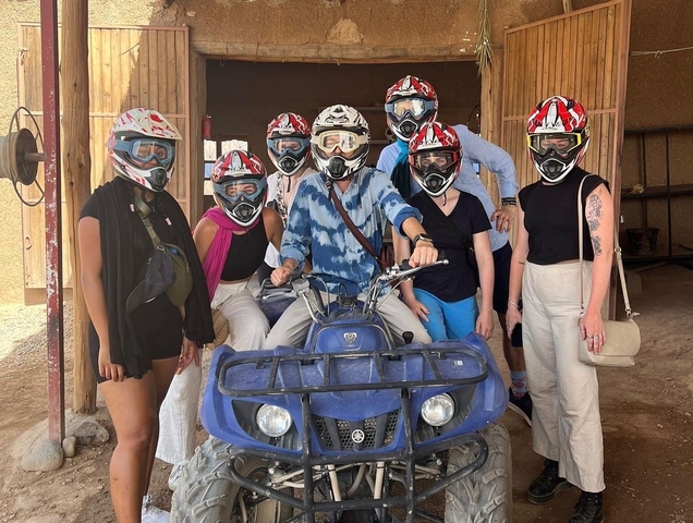 Group wearing helmets and posing with an ATV.