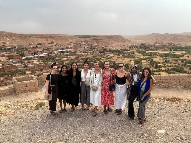 Group of women posing with a scenic background of a Moroccan town.