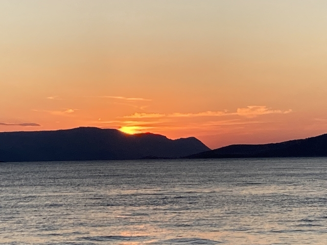      Sunset over a mountain range and water.
  