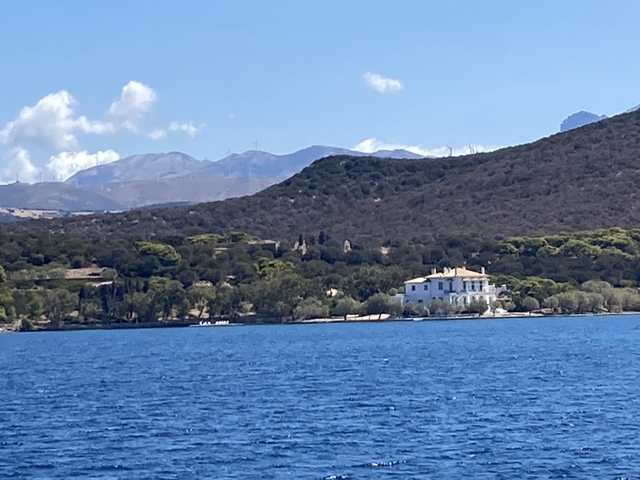       House by the coast with mountains in the background.
  