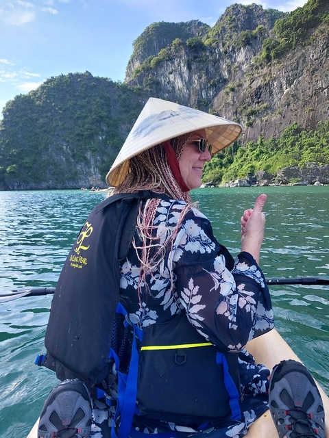 Person wearing a traditional hat on a boat ride in turquoise waters.